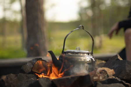 En kaffepanna värms över öppen eld i ett skogsparti.