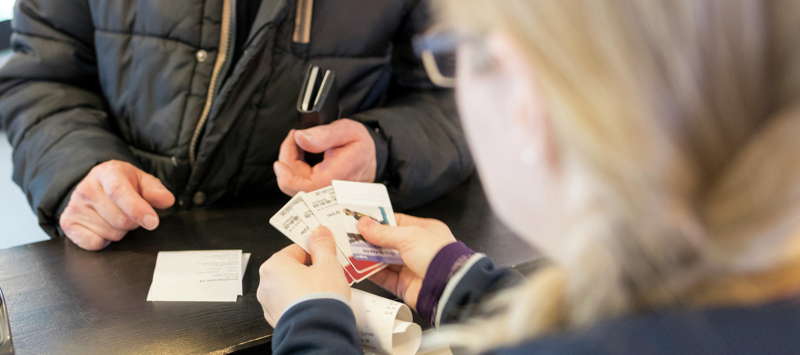 Person vid disk tar emot biljetter eller skipass från personal i jacka med Orsa Grönklitt-logga.